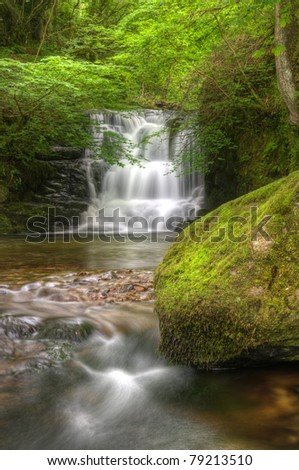 stock-photo-lush-green-forest-scene-with-long-exposure-blurred-waterfall-flowing-through-and-over-rocks-covered-79213510.jpg